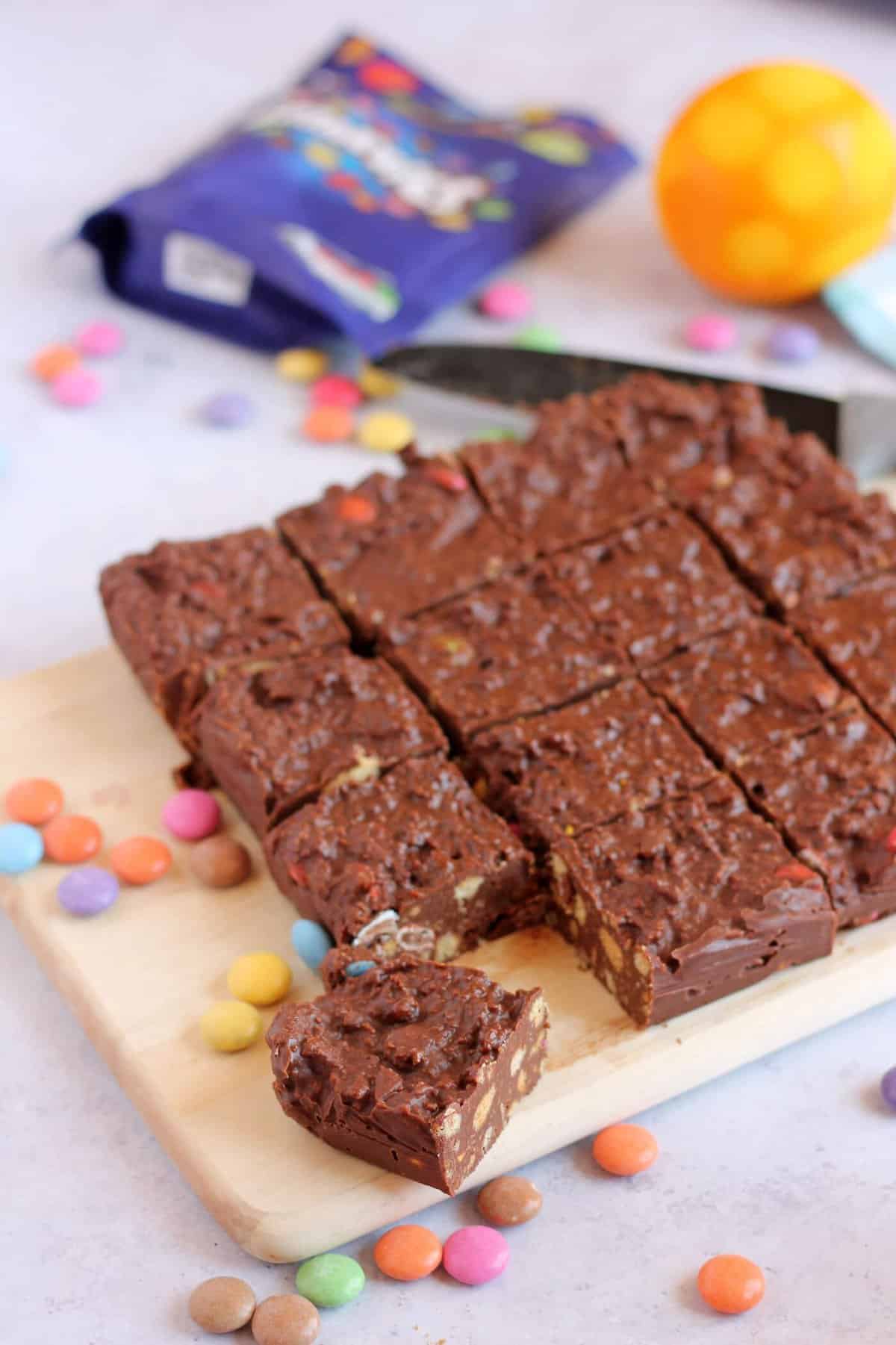 Chocolate biscuit cake, cut into squares on a chopping board.