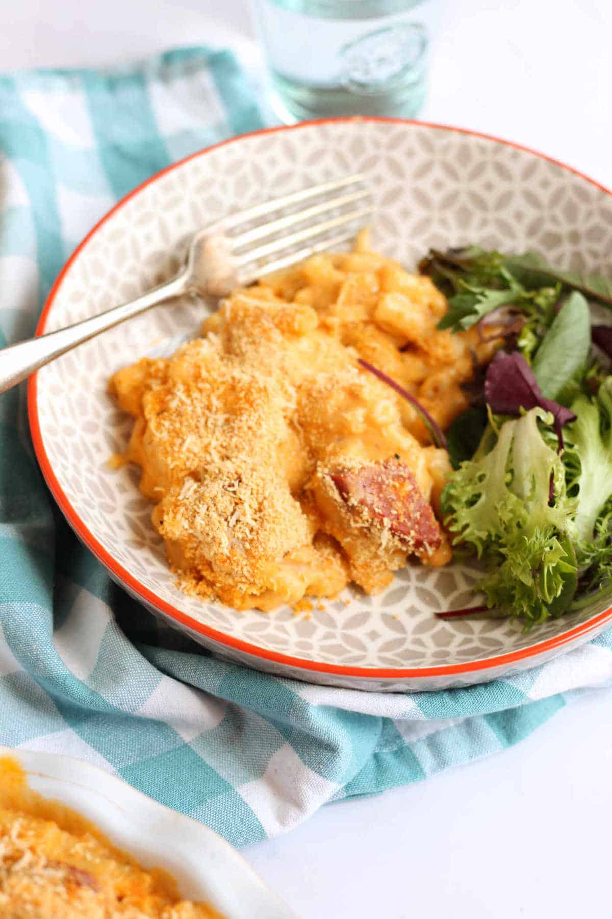 A bowl of macaroni cheese with side salad.