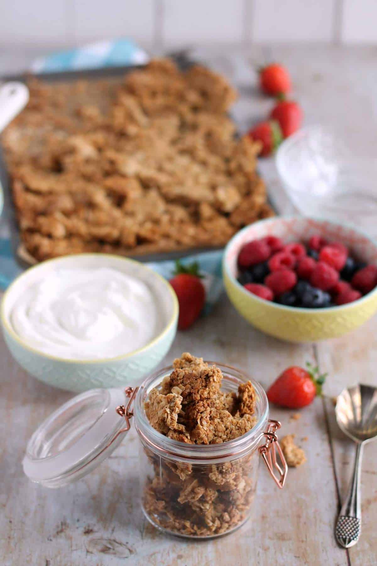 A kilner jar full of homemade peanut butter granola, with yogurt and fresh berries