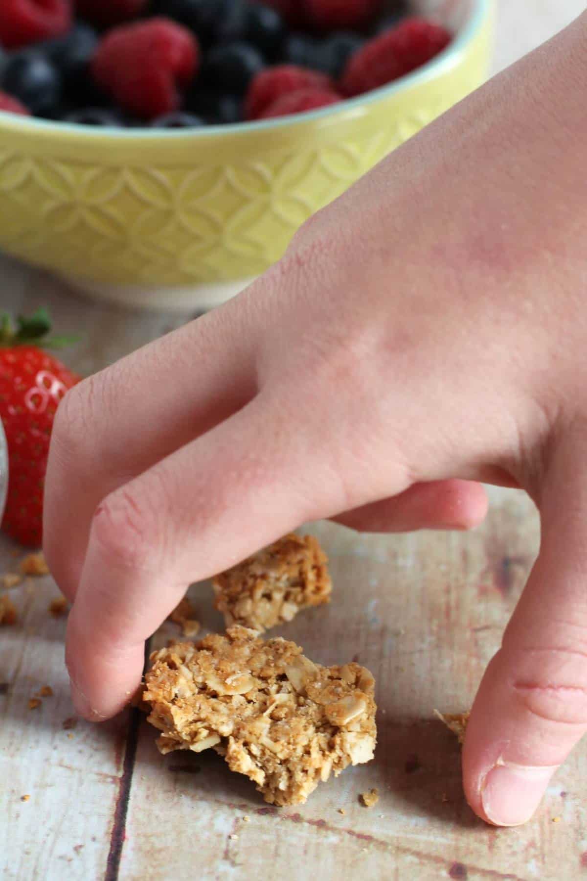 Child's hand picking up a piece of chunky granola