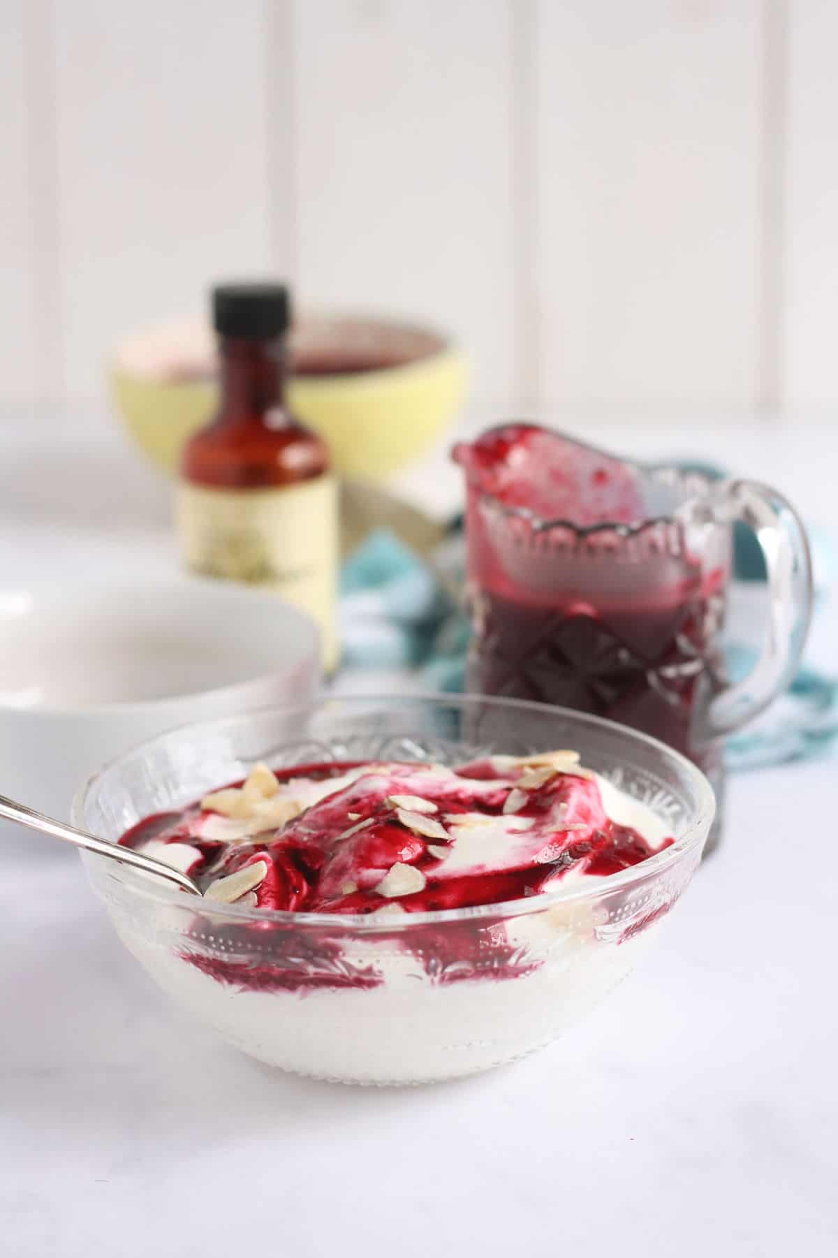 A bowl of Greek yogurt with fruit coulis and flaked almonds.