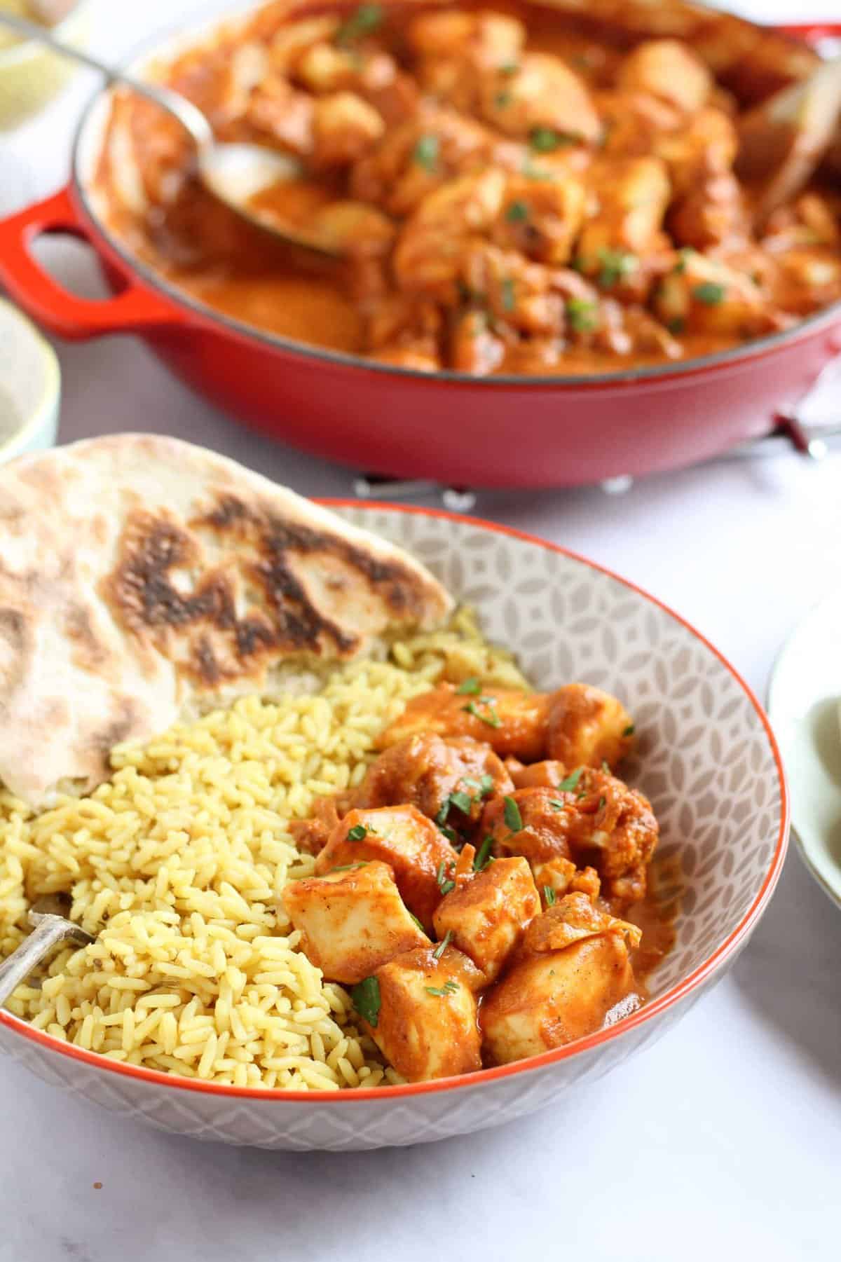 A bowl of curry with pilau rice and naan bread.