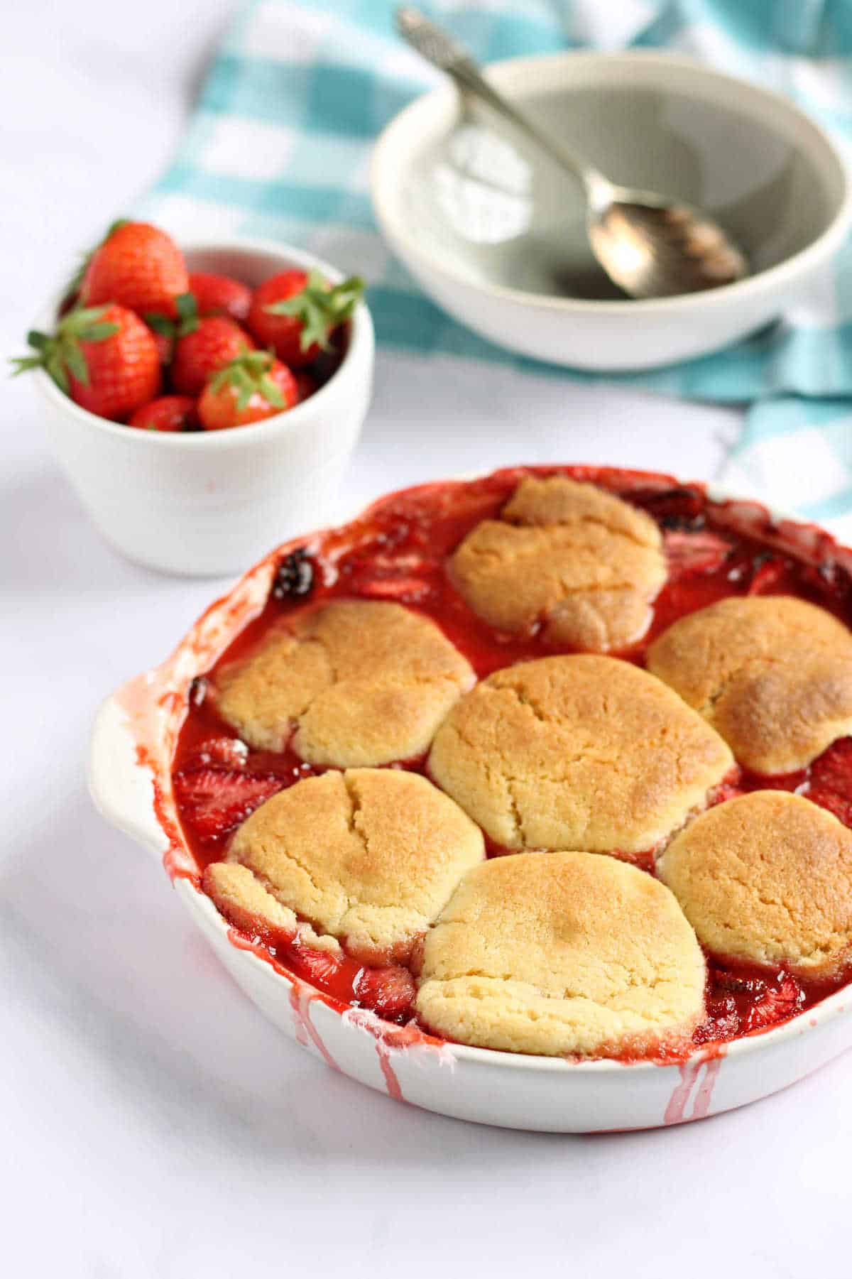 This easy strawberry cobbler recipe is a delicious summery dessert, that celebrates strawberry season in style. The golden cobbler topping encases sweet juicy strawberries underneath. Serve warm with ice-cream for a taste of summer, whatever the time of year.