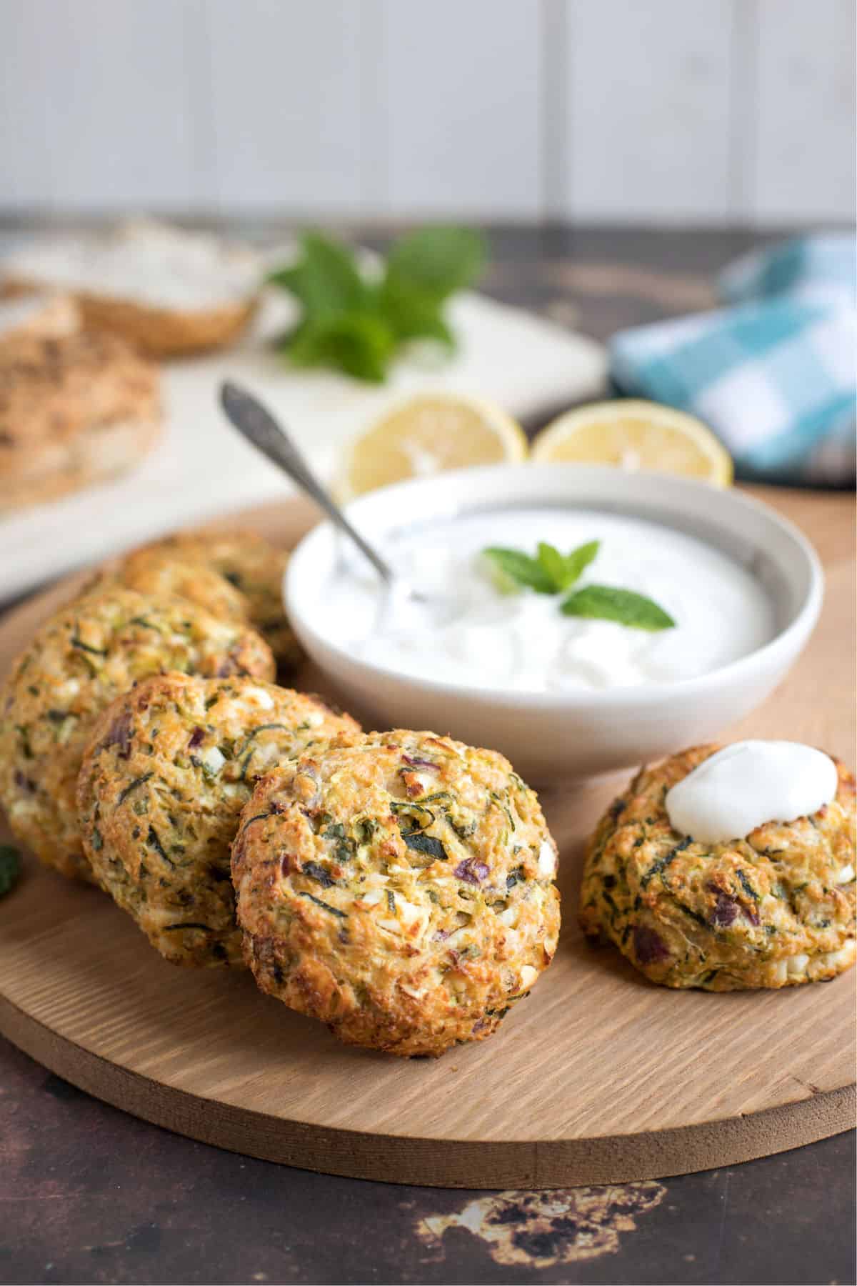 Courgette burgers on a serving platter with a bowl of tzatziki
