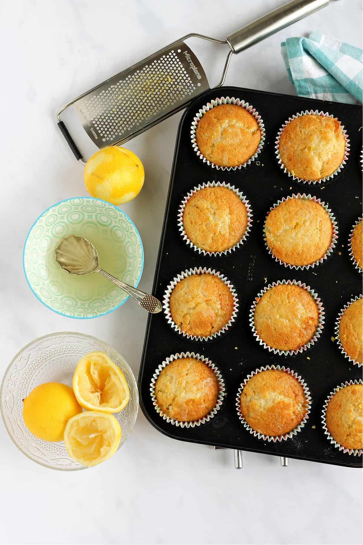 Overhead shot of lemon drizzle muffins in baking tin.