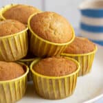 Lemon drizzle muffins on a white cake stand.