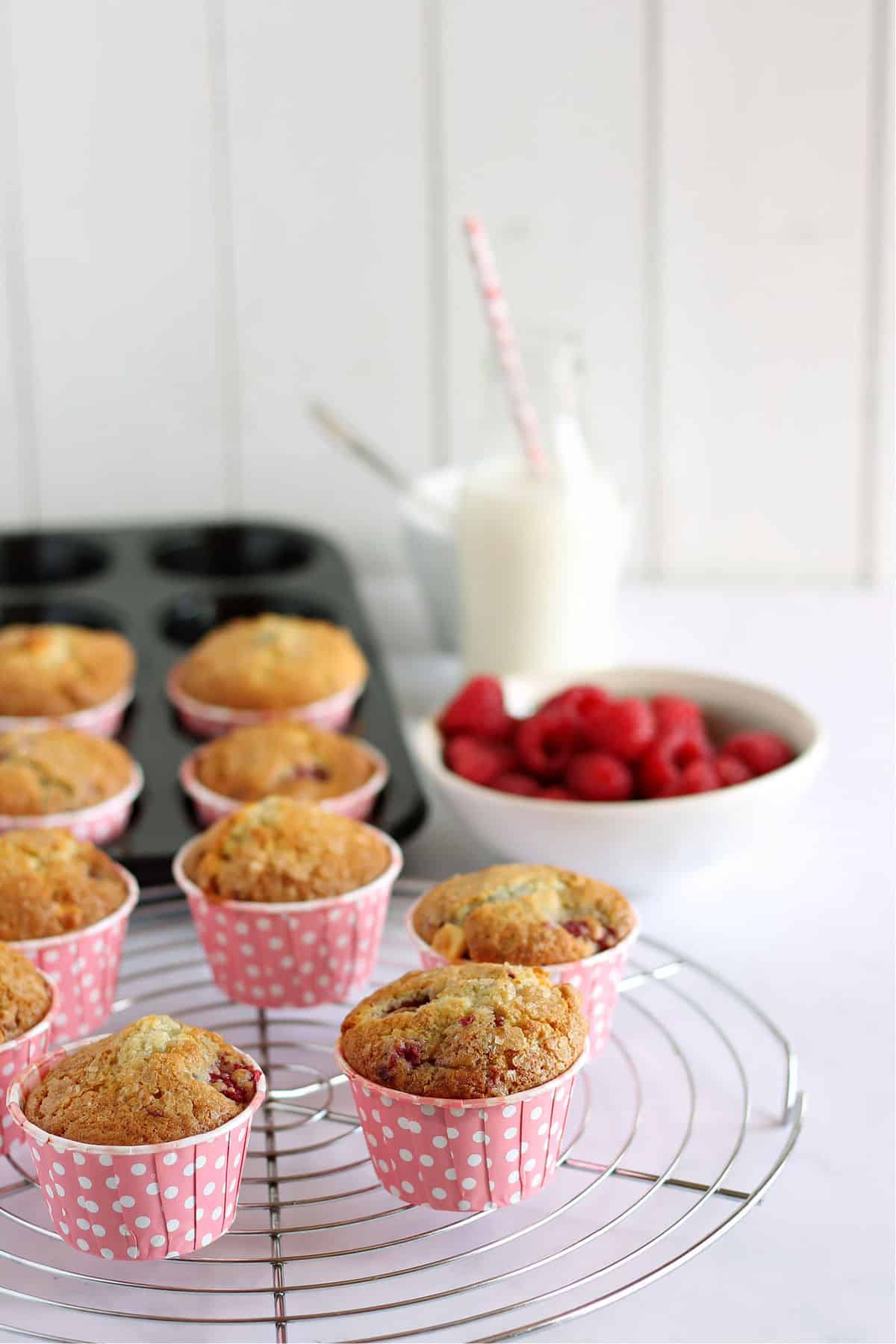 muffins with a bowl of raspberries in the background