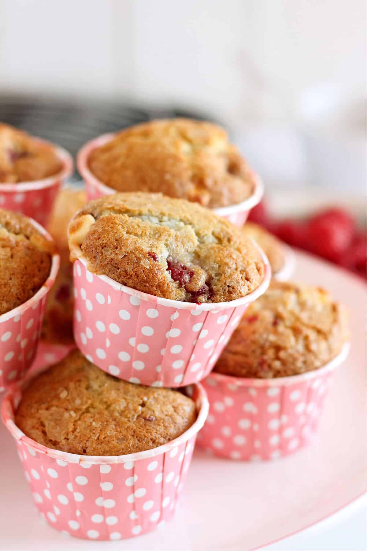 Raspberry muffins studded with white chocolate, piled on a cake stand.