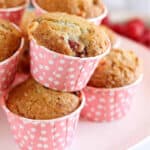 Raspberry and white chocolate muffins on a white cake stand.