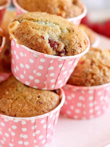 Raspberry and white chocolate muffins on a white cake stand.