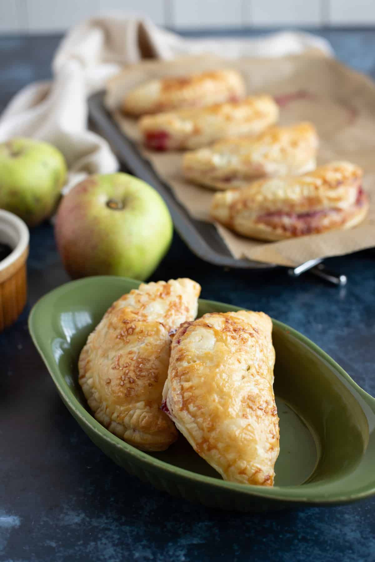 A close up of 2 baked turnovers in a serving dish.