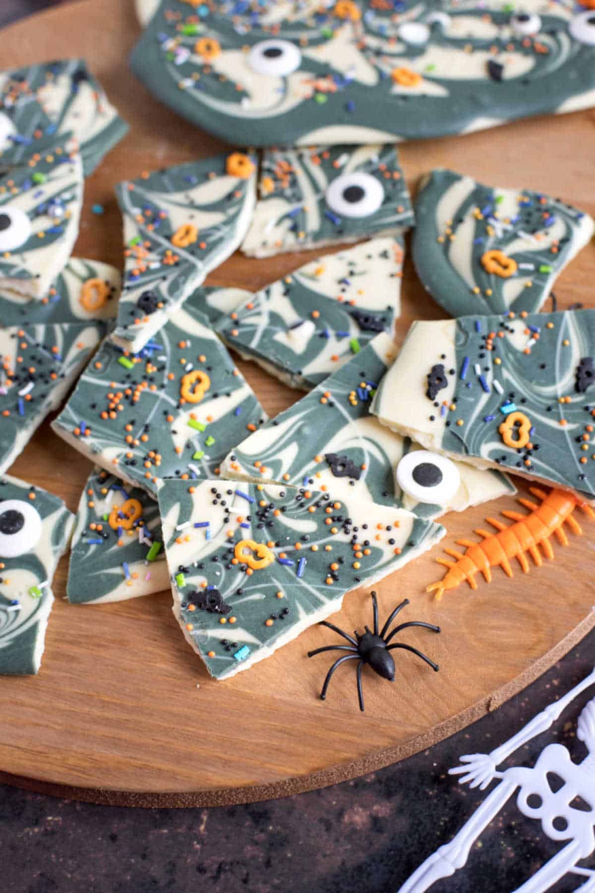 Broken pieces of chocolate bark decorated for Halloween with sprinkles and edible eyes.