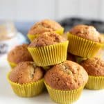 Peanut butter and banana muffins on a cake stand with a jar of peanut butter in the background.