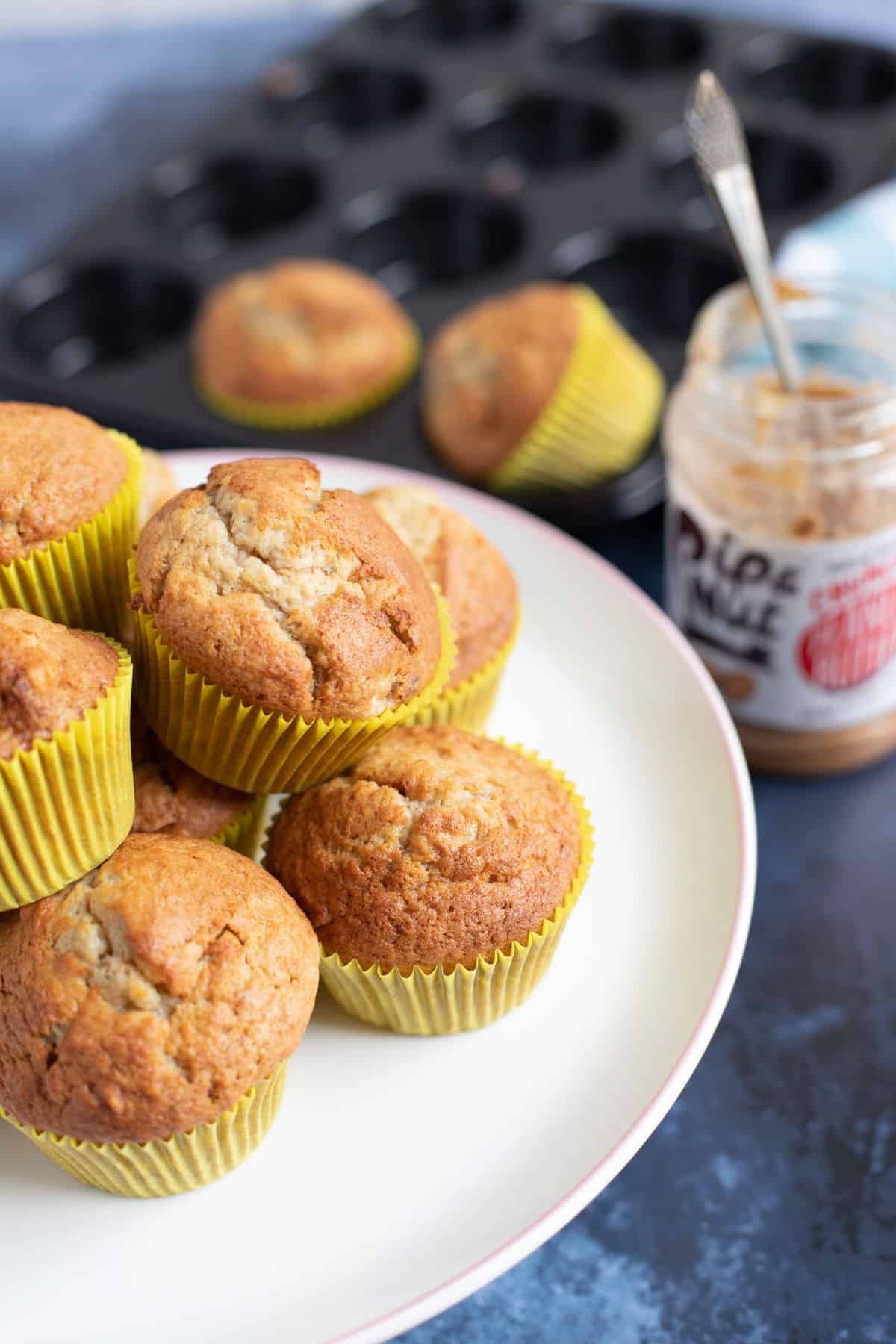 Banana muffins with peanut butter chips stacked on a cake plate.