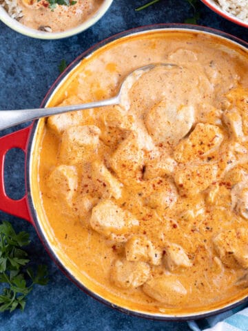 A pan of creamy chicken mushroom stroganoff with a metal spoon in it.