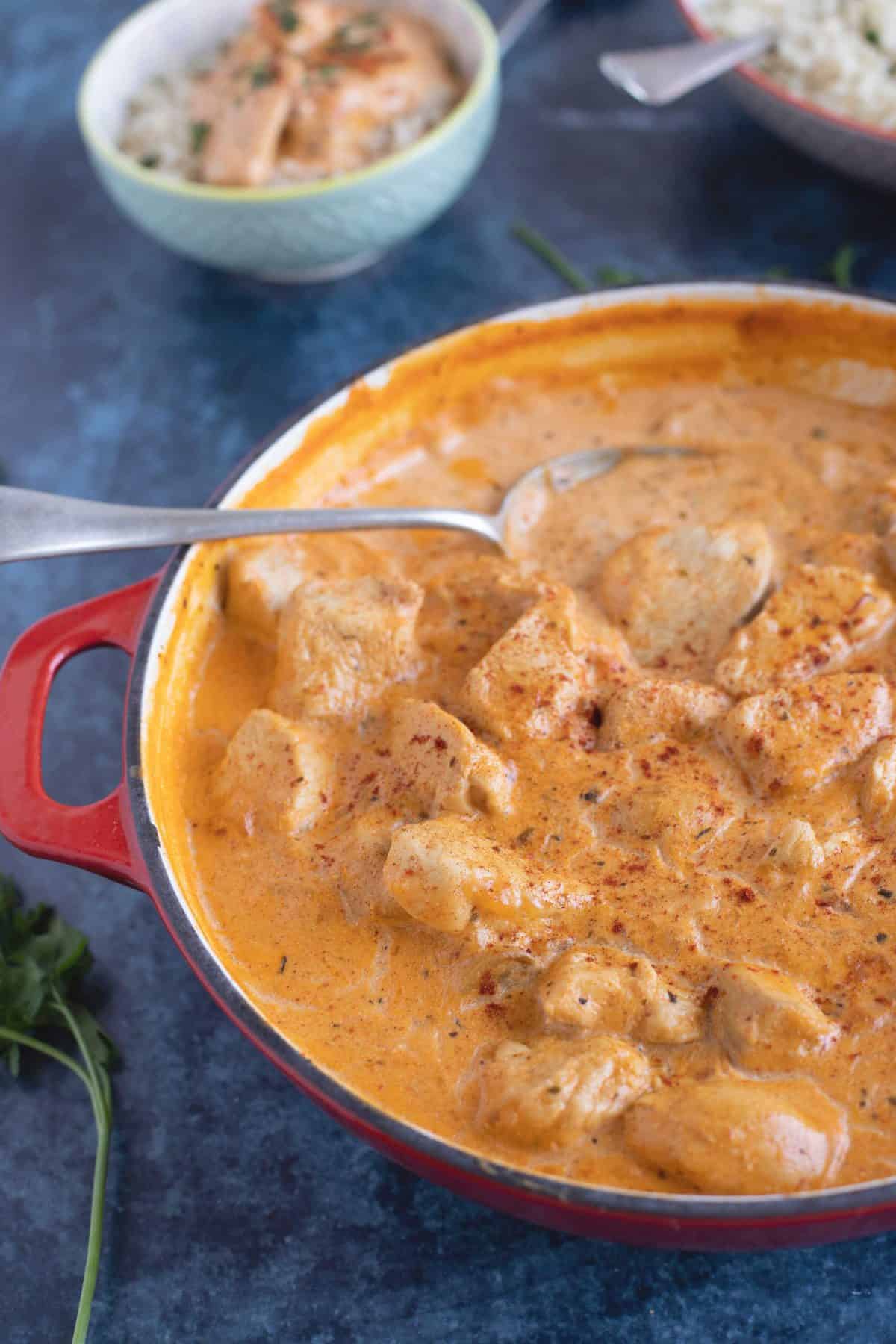 Chicken stroganoff with mushrooms in a red pan.