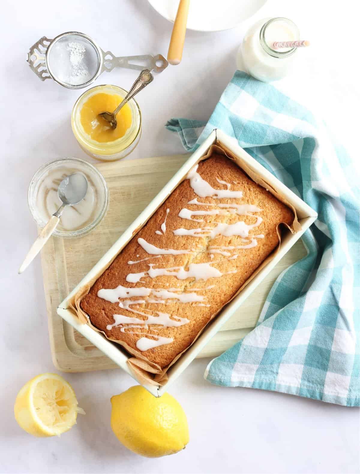 Lemon curd loaf cake in a green loaf tin drizzled with a lemon icing.