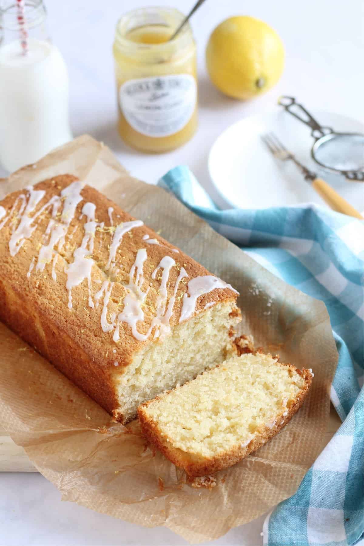 A slice of lemon curd loaf cake with the whole cake in the background.