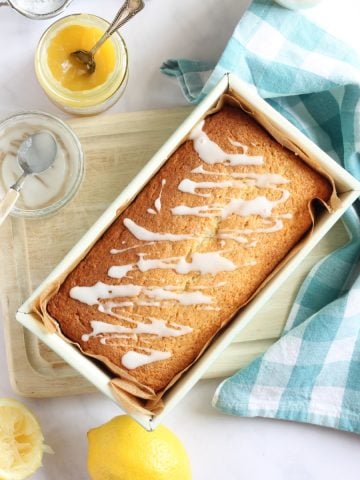 Lemon Curd Loaf Cake on a cake board ready for slicing.