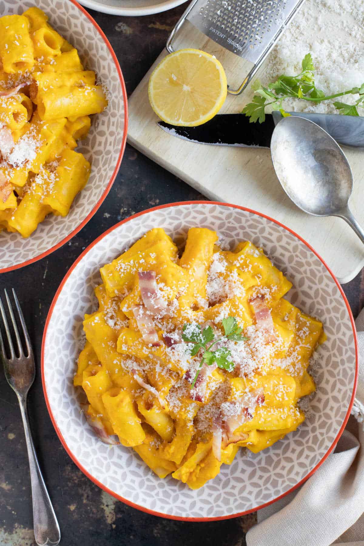 A bowl of creamy bacon and pumpkin pasta sprinkled with Parmesan.