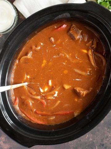 Slow cooker beef goulash in a black slow cooker basin.