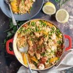 Prawn and chorizo paella with lemon wedges.