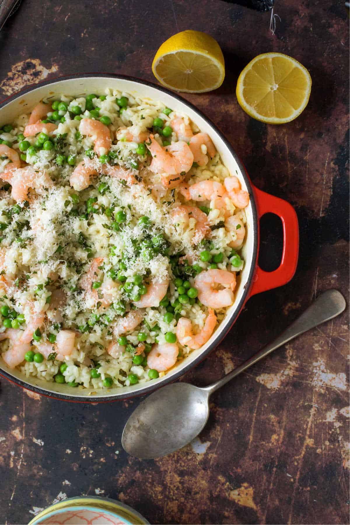 Prawn and pea risotto with fresh lemon wedges, ready for serving.