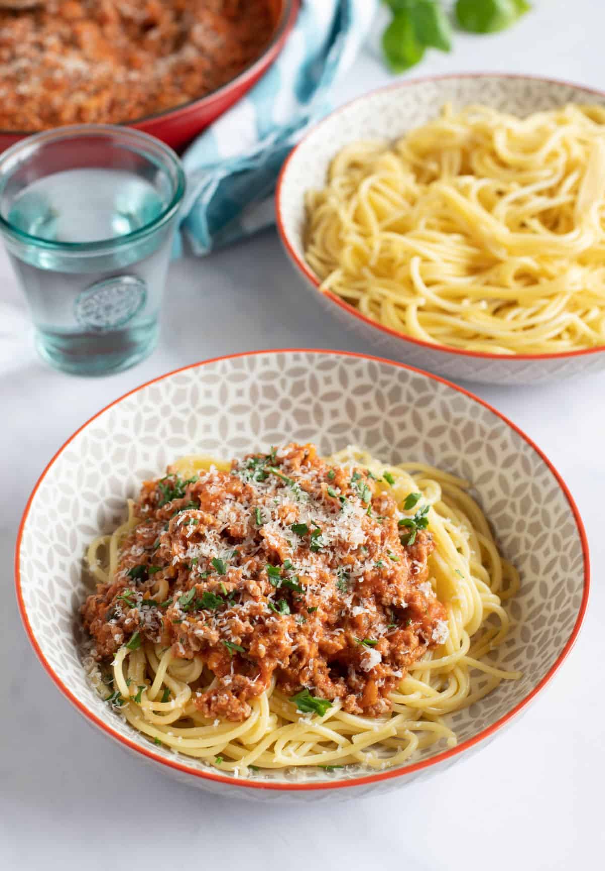 A bowl of turkey bolognese served with spaghetti and grated parmesan.