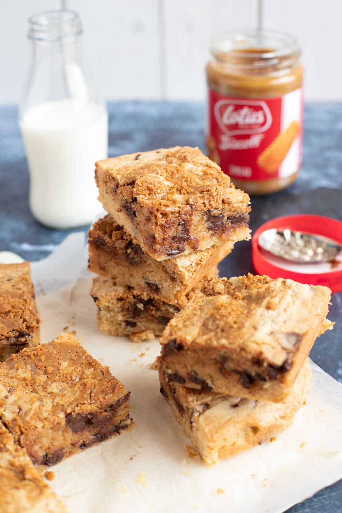 Cut blondies on a wooden board with a glass of milk in the background.