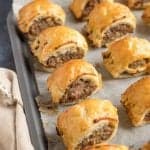 Puff pastry sausage rolls on a baking sheet.