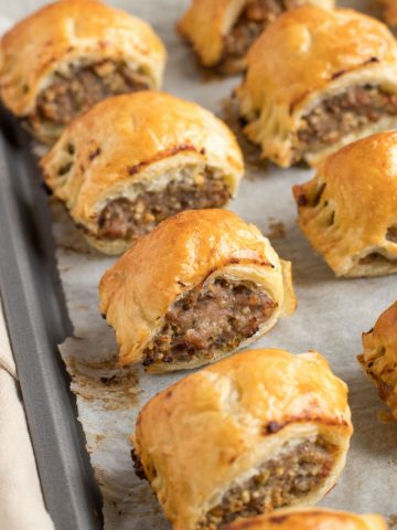 Puff pastry sausage rolls on a baking sheet.