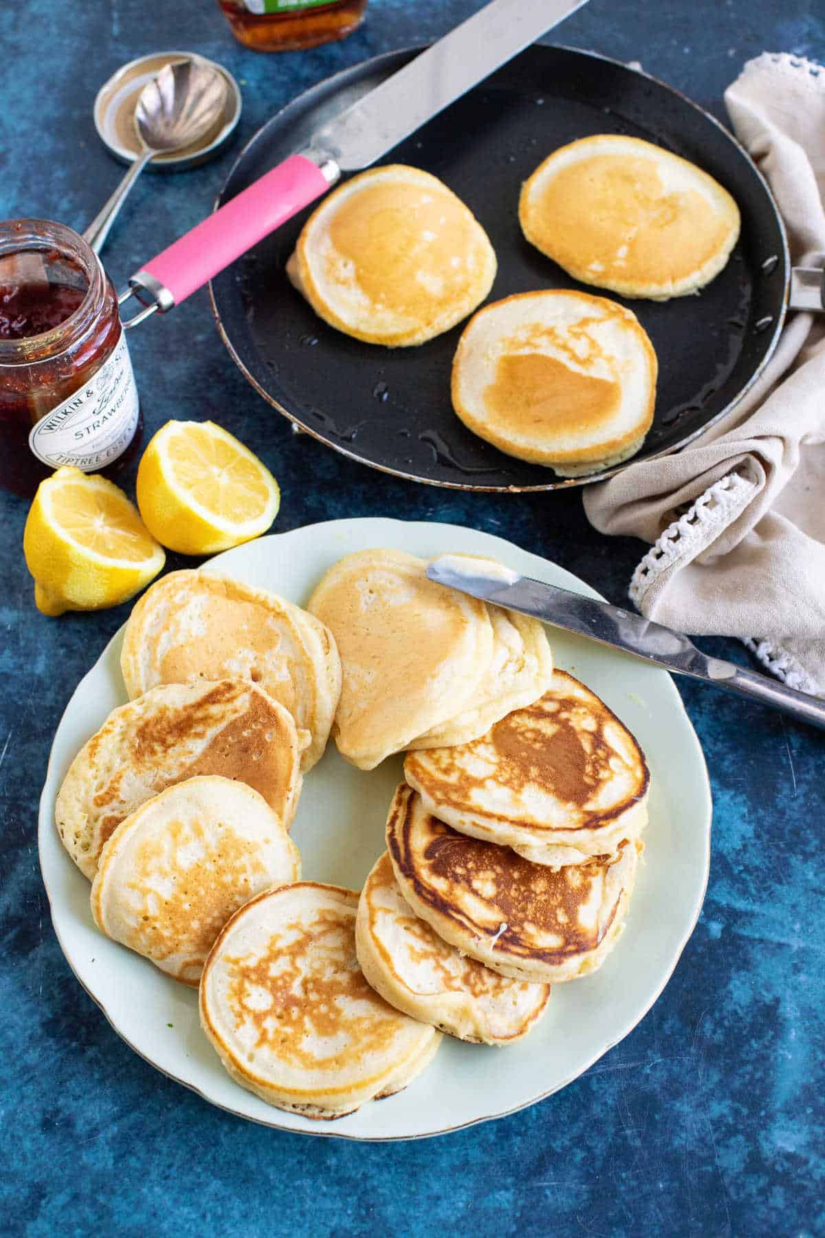 Drop scones served on a plate with butter and jam.