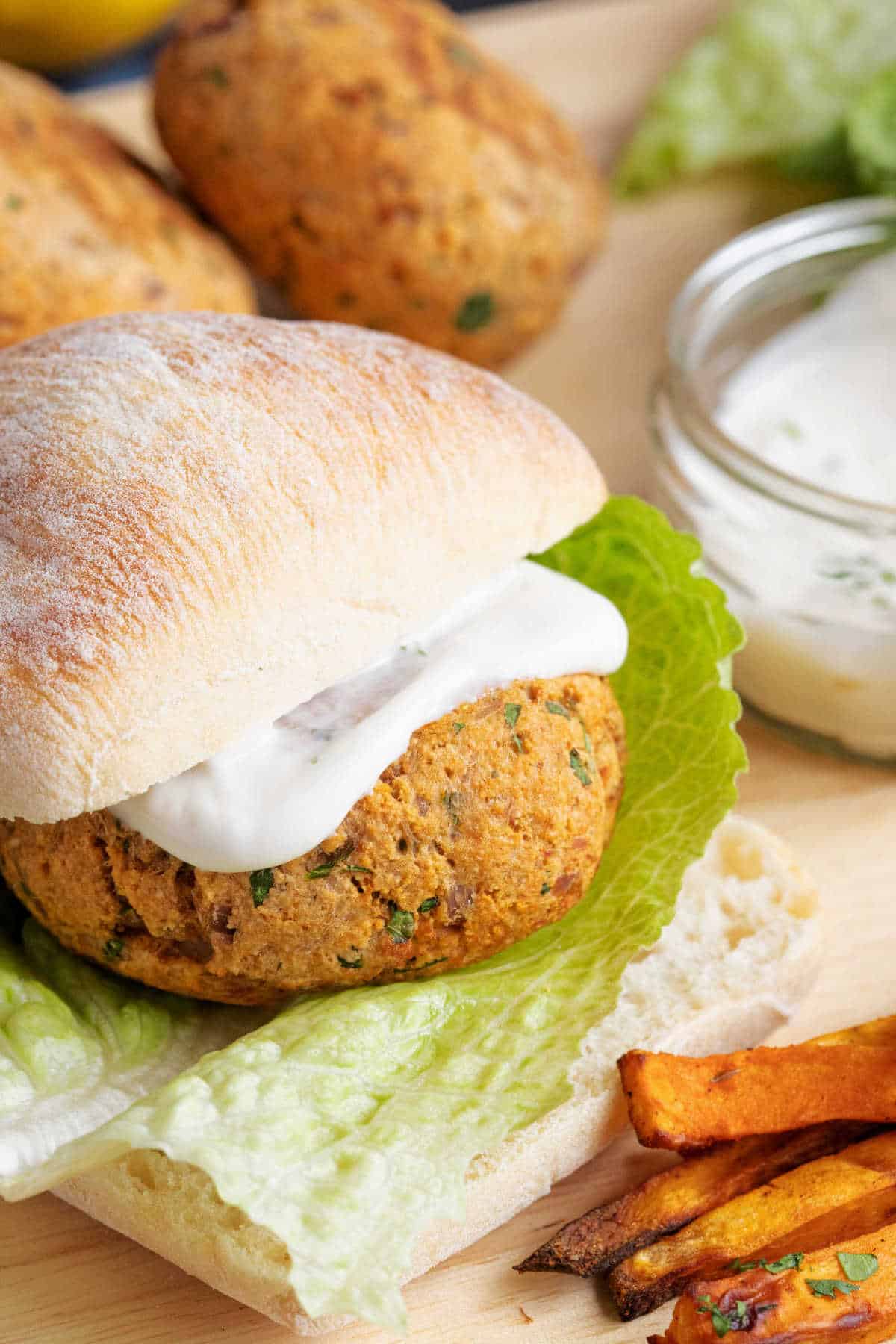 A tuna pattie served on a ciabatta roll with salad.