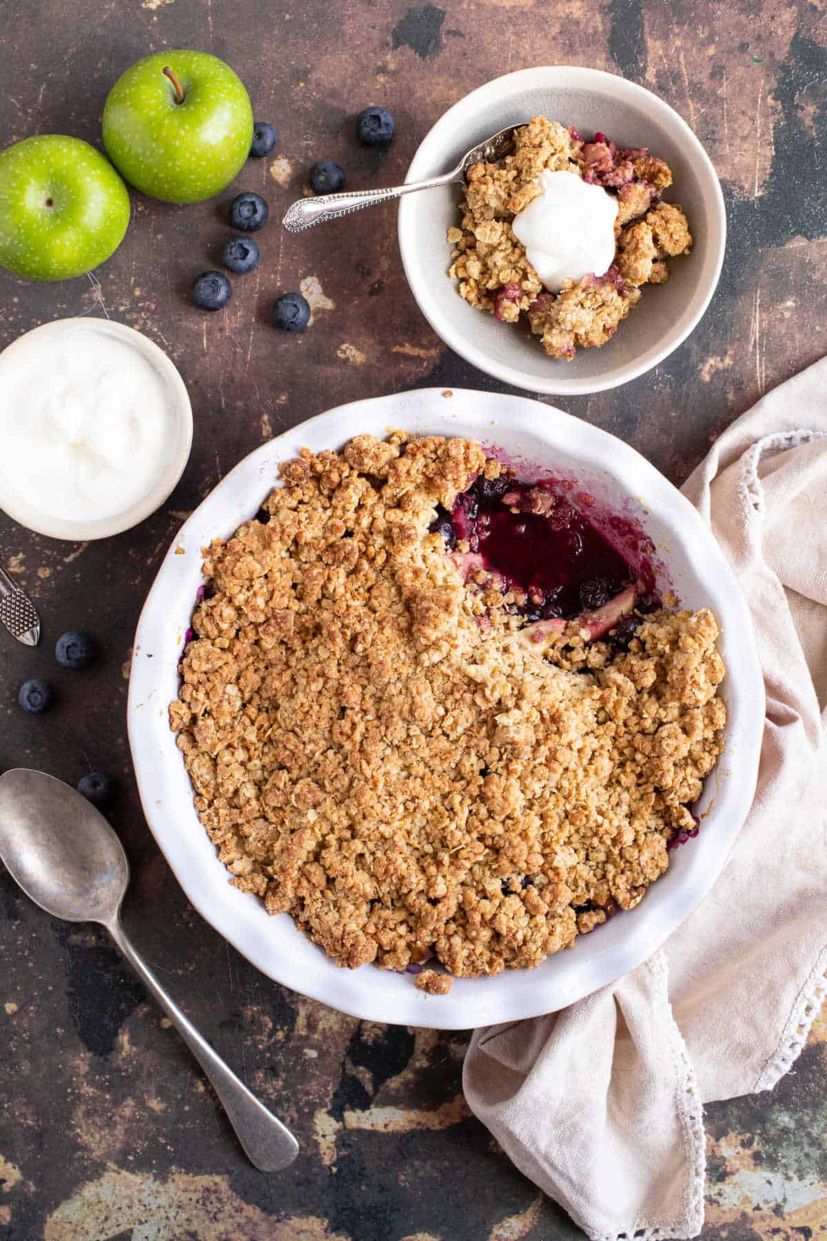 Apple and blueberry crumble in a bowl served with yogurt.