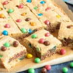 M&M Cookie Bars cut into slices on a board.