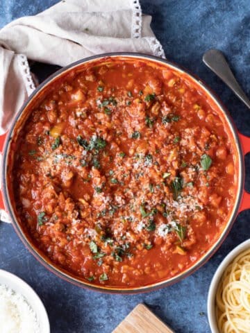 Quorn bolognese in a red pan with grated Parmesan.