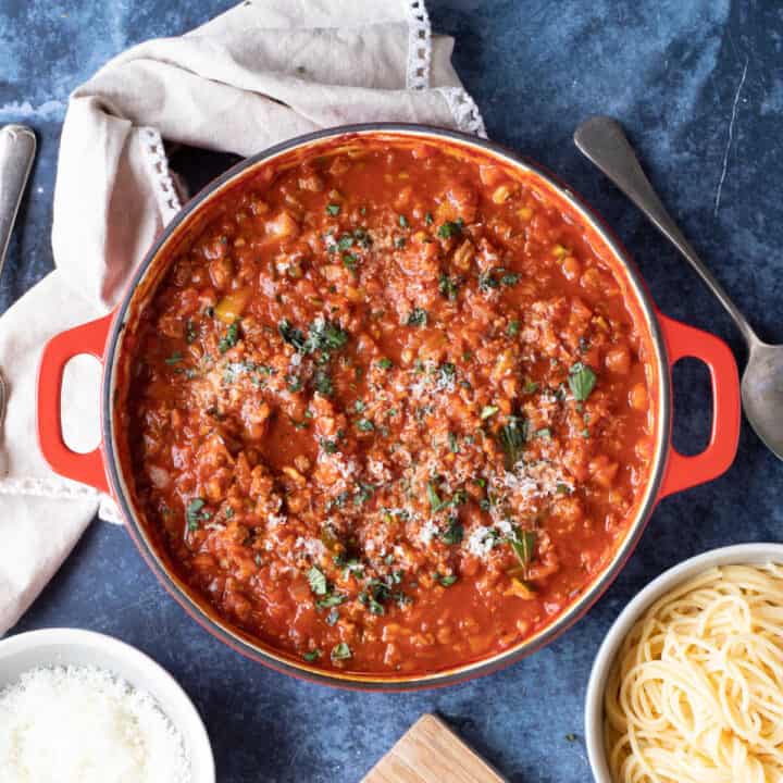 Quorn bolognese in a red pan with grated Parmesan.