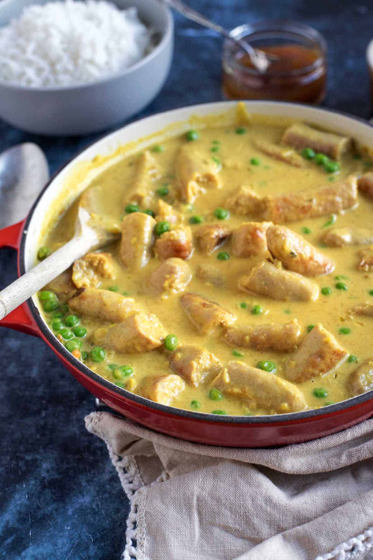 Sausage curry in a red pan.