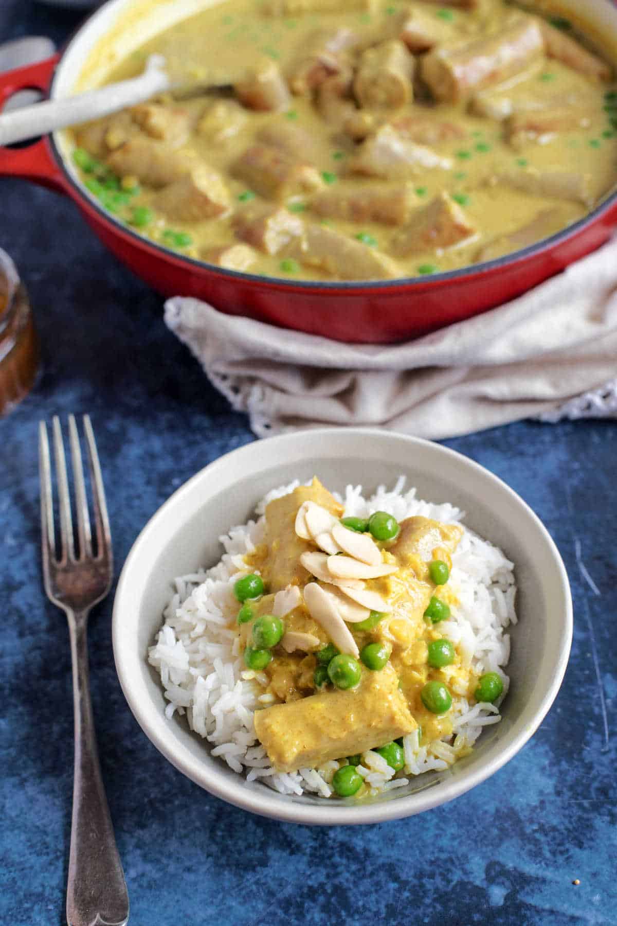 A bowl of sausage curry on a bed of rice.