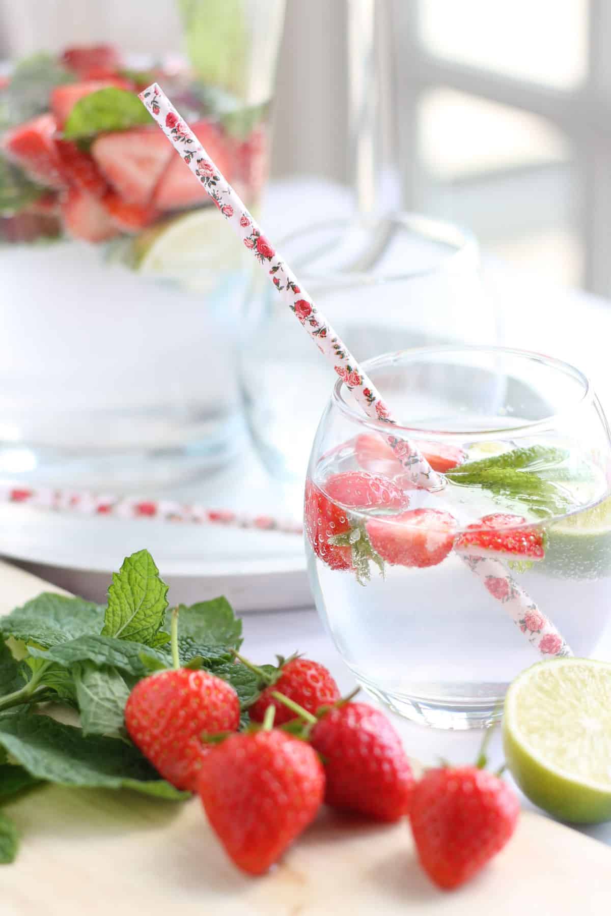 A glass of strawberry mojito cooler with a paper straw.