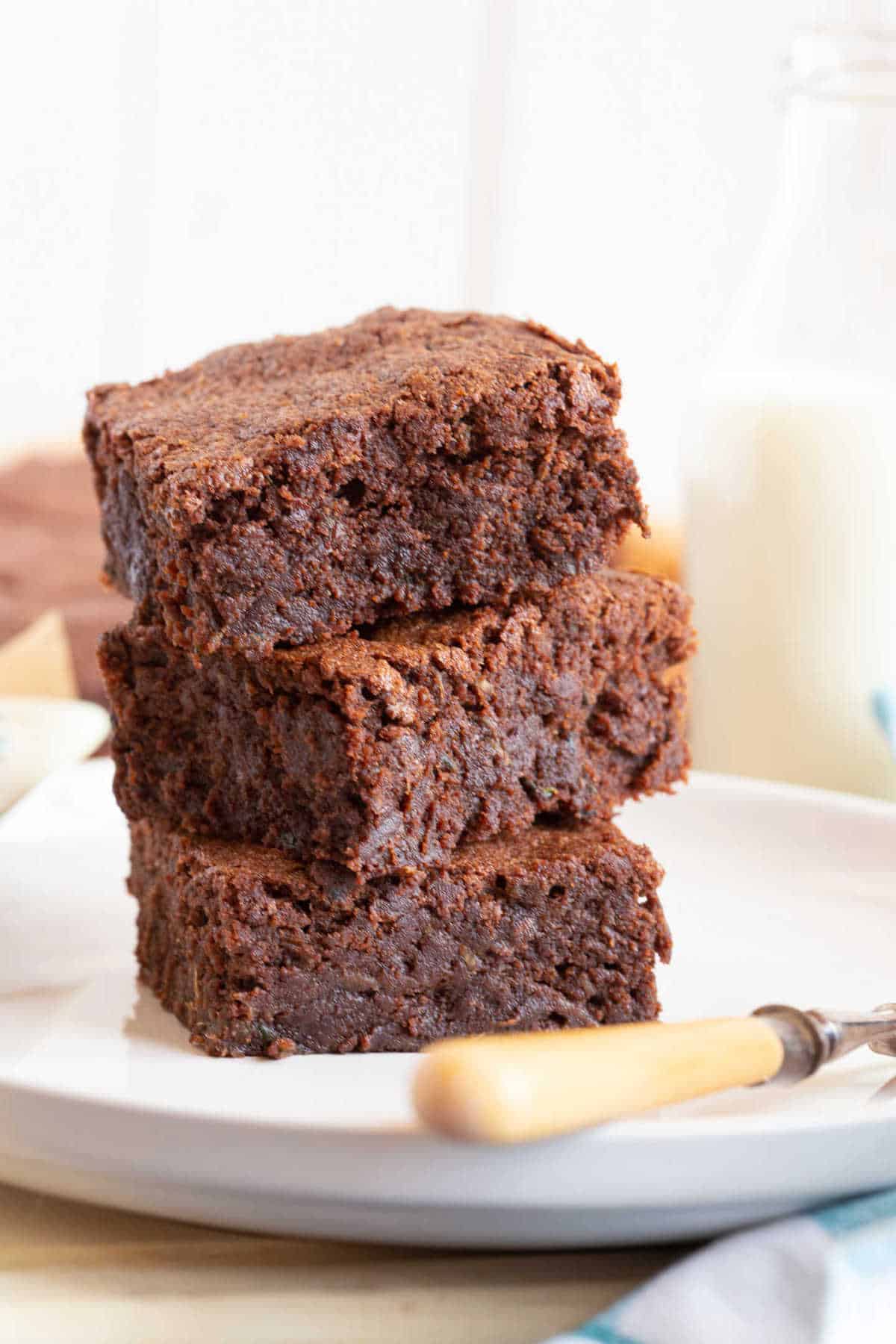 A stack of three courgette brownies on a plate.