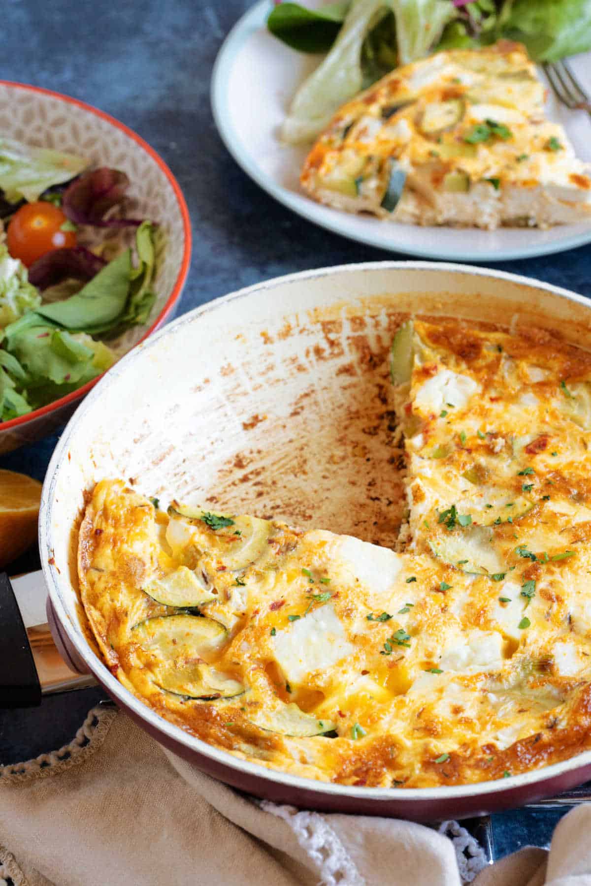 Courgette and feta frittata in a red frying pan.