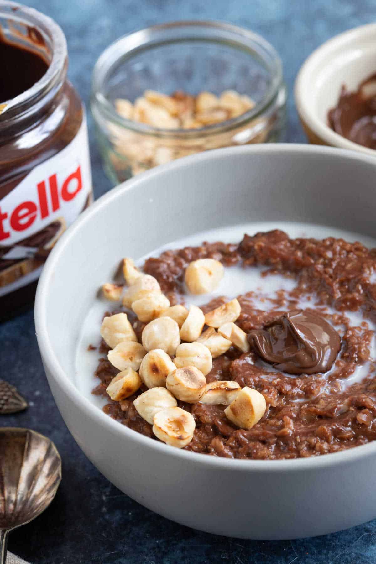 A bowl of Nutella porridge with a jar of Nutella in the background.
