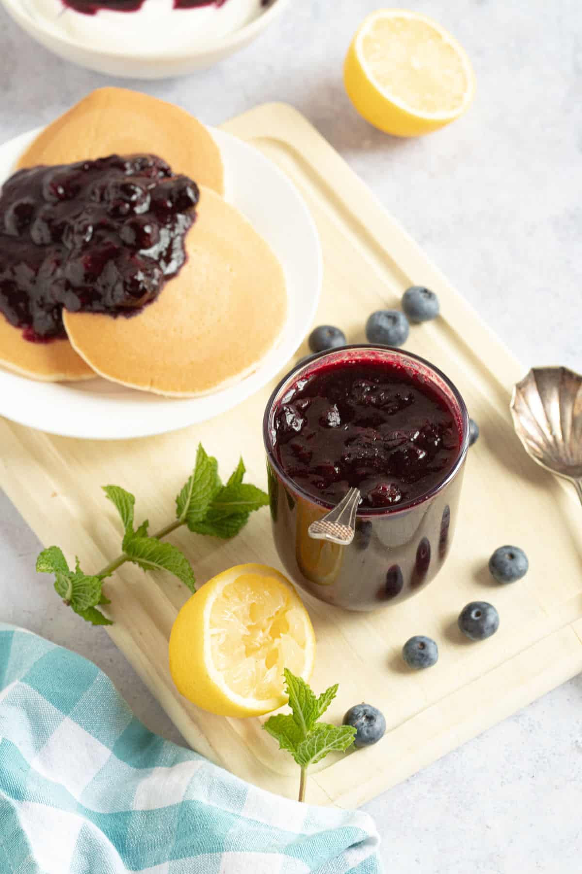 Blueberry compote in jar and spooned onto pancakes.