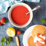 Strawberry coulis in a bowl with pancakes and yogurt.