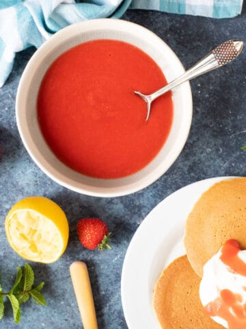 Strawberry coulis in a bowl with pancakes and yogurt.