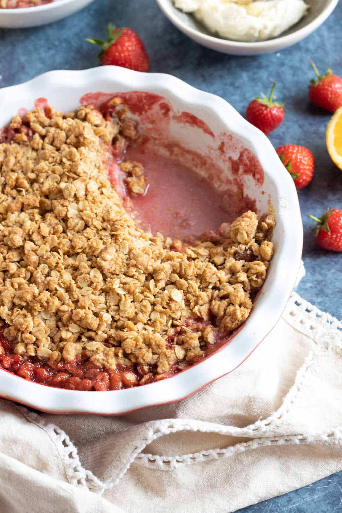 Strawberry crumble in a pie dish with cream.