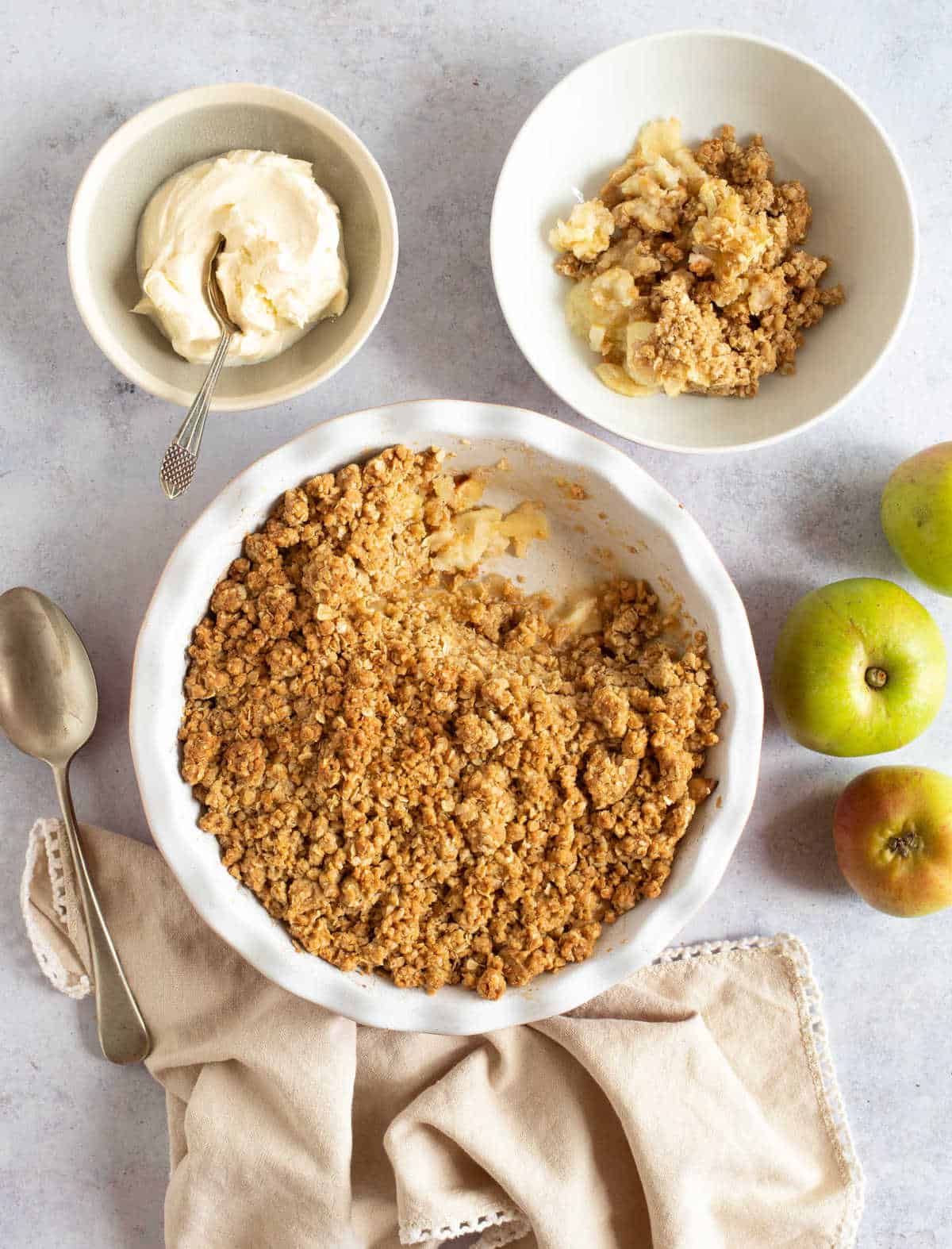 Easy cinnamon apple crumble in a red pie dish with whipped cream.