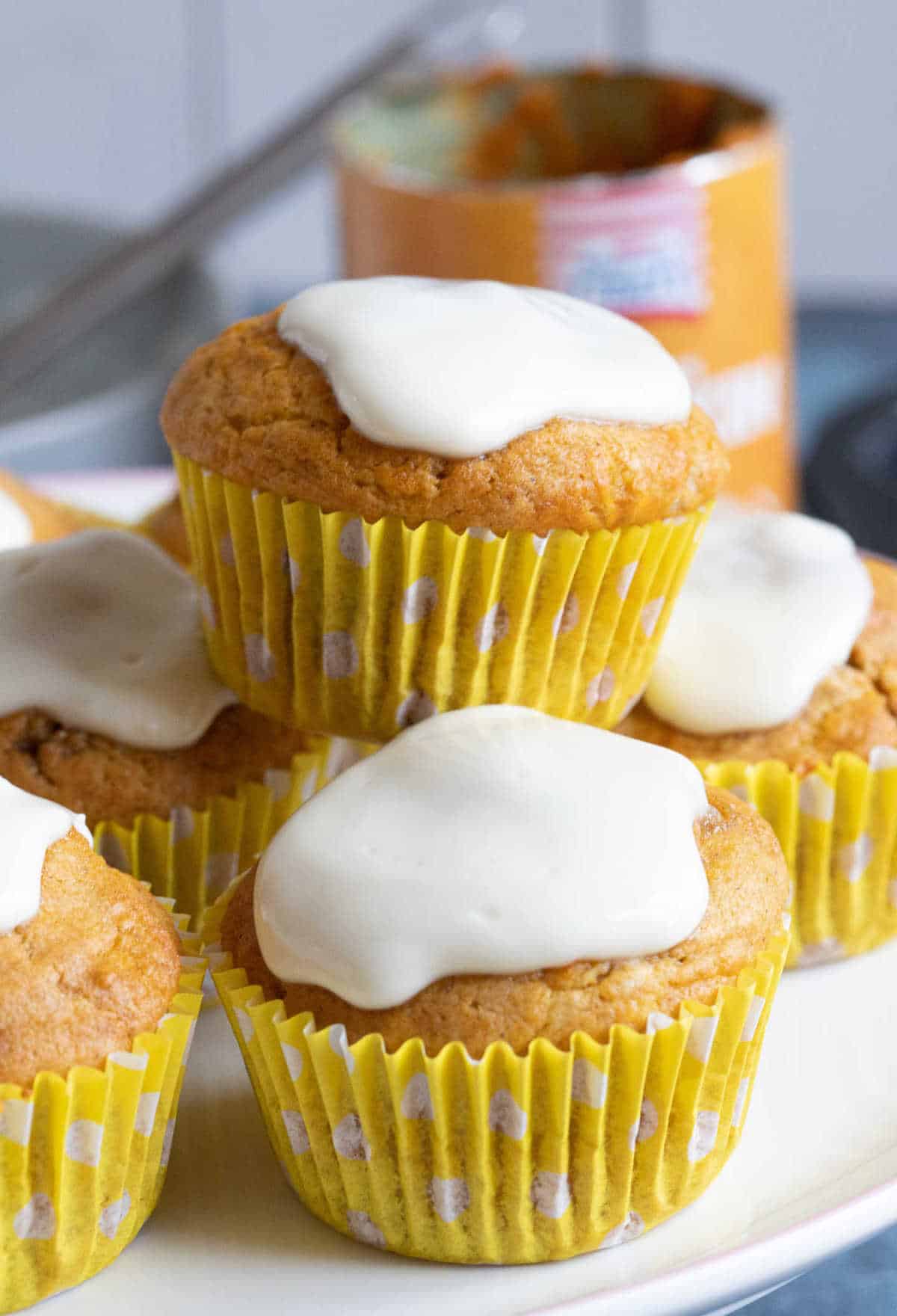 Spiced pumpkin muffins with cream cheese frosting on a cake stand.