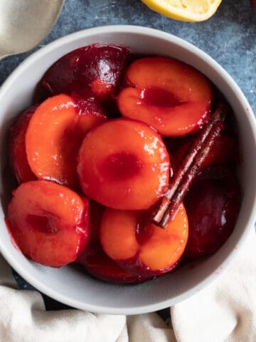 Stewed plums in a bowl with cinnamon.